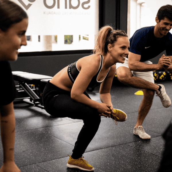 Estiramientos de fitness en grupo con entrenador sonriente.