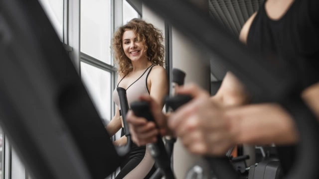 lächelnde frau am trainingsgerät im fitnessstudio