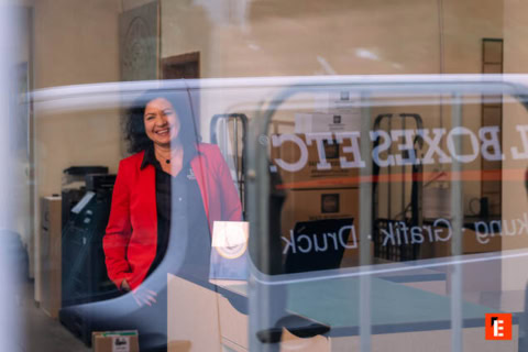 frau im roten blazer hinter dem versandladen schaufenster