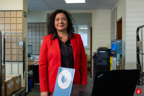 frau im roten blazer mit auszeichnung im büro