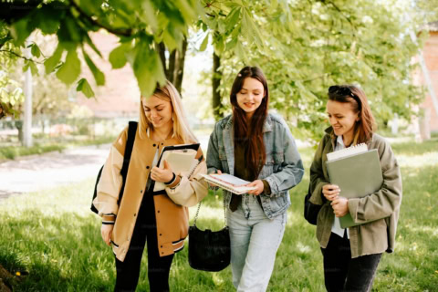 estudiantes caminando y revisando apuntes en el campus