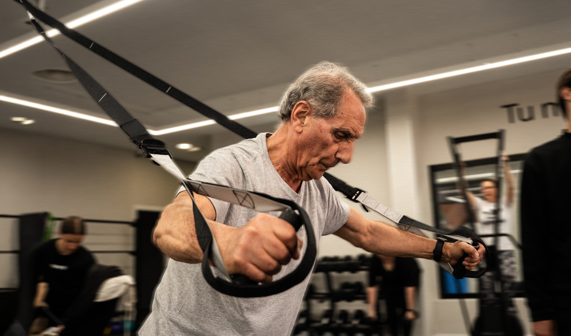 hombre mayor entrenando con trx en gimnasio