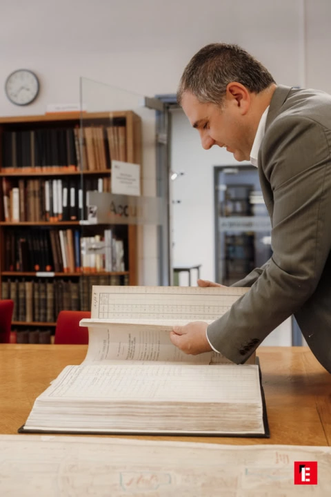 chercheur aux archives feuilletant un registre historique