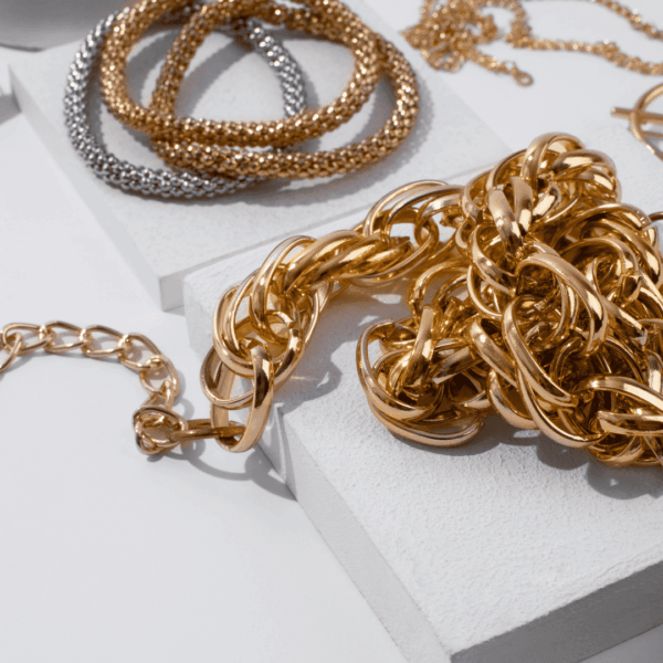 cadena dorada, pulseras y perla en fondo minimalista