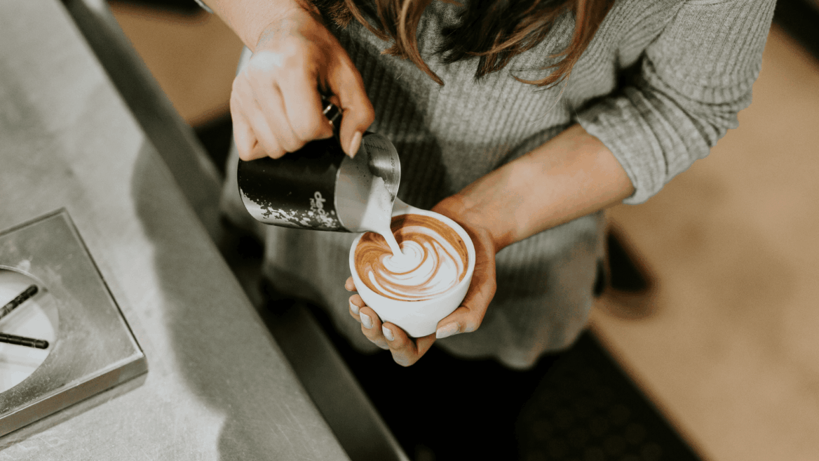 barista pouring latte art over espresso