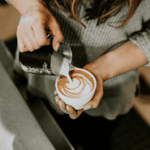barista pouring latte art over espresso