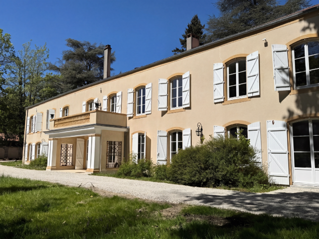 maison ocre à volets blancs et jardin ensoleillé