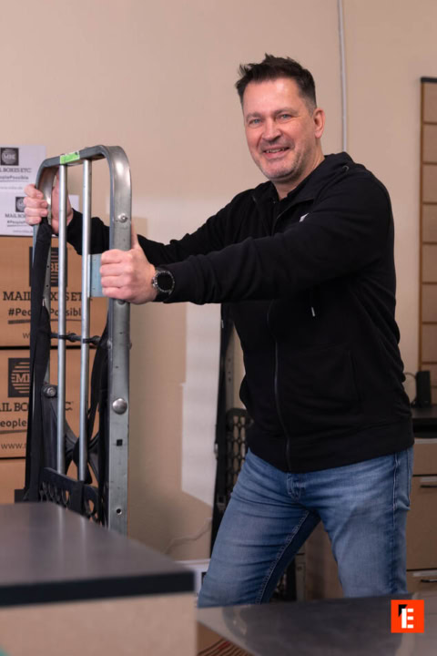 lächelnder mann mit handwagen beim umzug