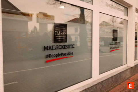 mbe‑fassade mit logo und straßenreflexionen