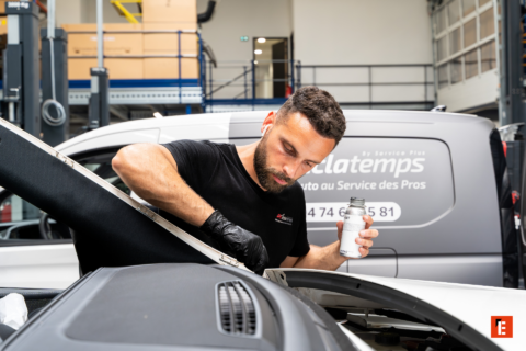 mécanicien en atelier applique un produit sous le capot