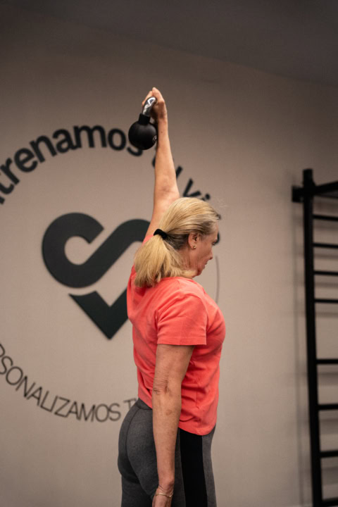 mujer realizando press con kettlebell sobre la cabeza