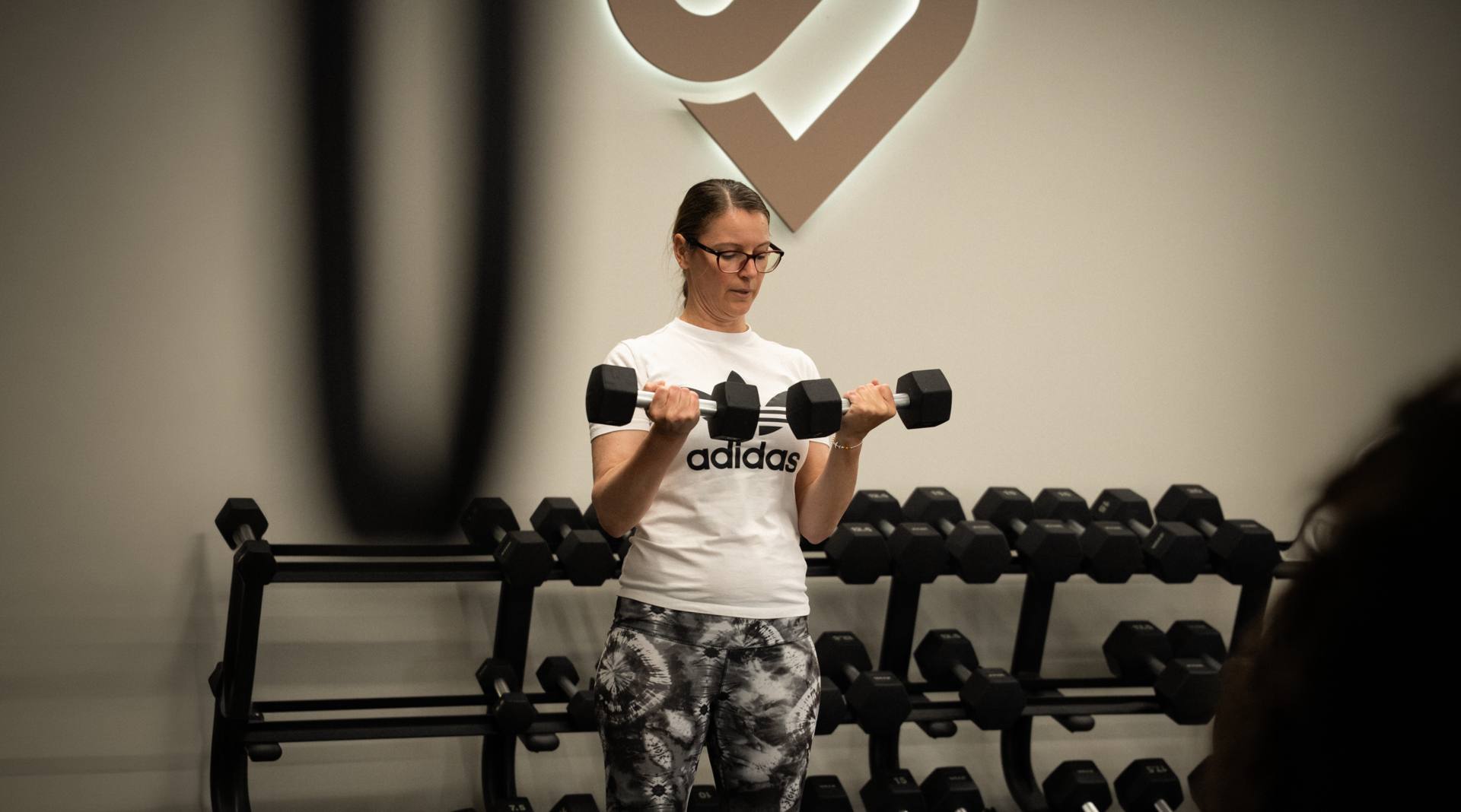 mujer entrenando bíceps con mancuernas en gimnasio
