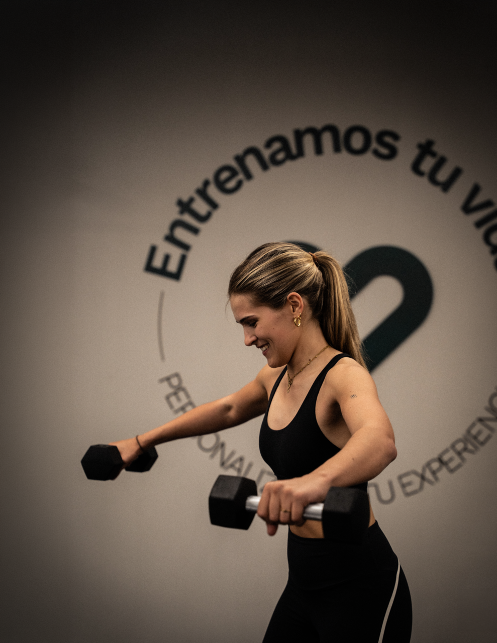 mujer entrenando hombros con pesas en gimnasio