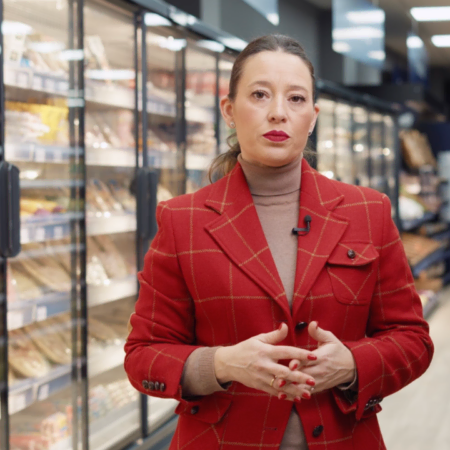 presentadora con blazer rojo y micrófono en supermercado