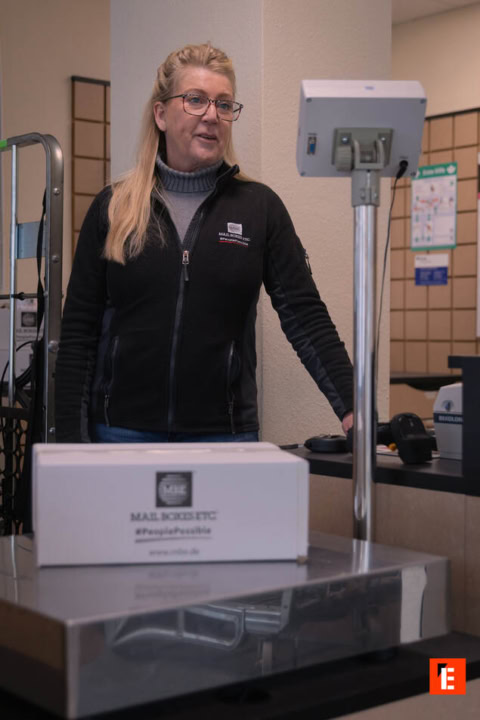 mitarbeiterin wiegt paket bei mail boxes etc