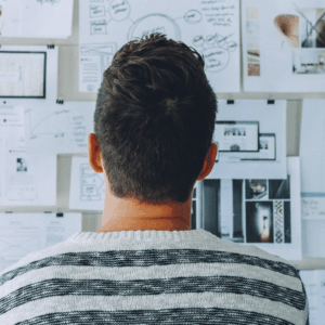 persona mirando tabla con papeles escritos