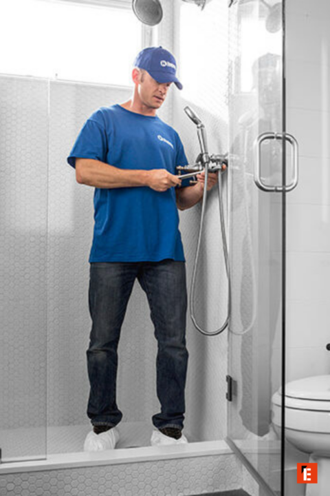 plumber adjusting chrome shower valve in modern bathroom