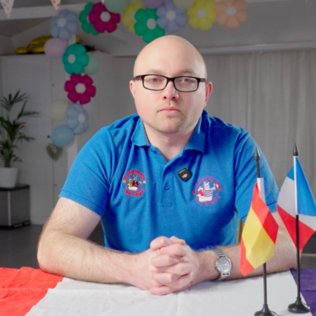 seated presenter in blue polo with flags