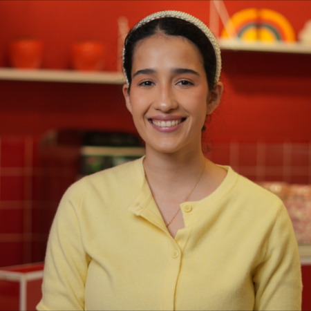 mujer sonriente en cafetería con cárdigan amarillo