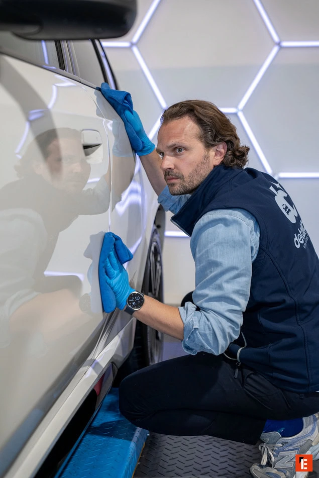 technicien de detailing polissant une voiture blanche