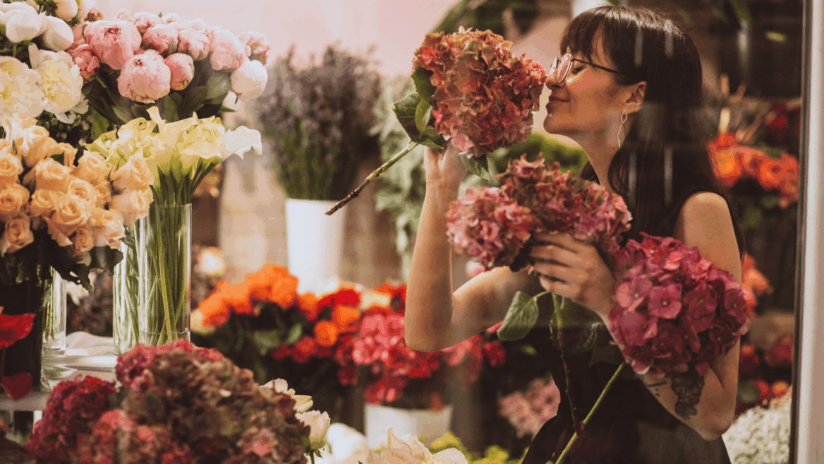 mujer oliendo hortensias en floristería