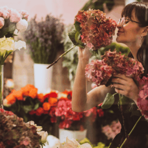 mujer oliendo hortensias en floristería