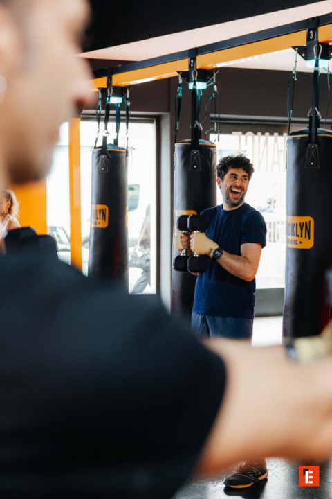 uomo sorridente con manubri in palestra boxe