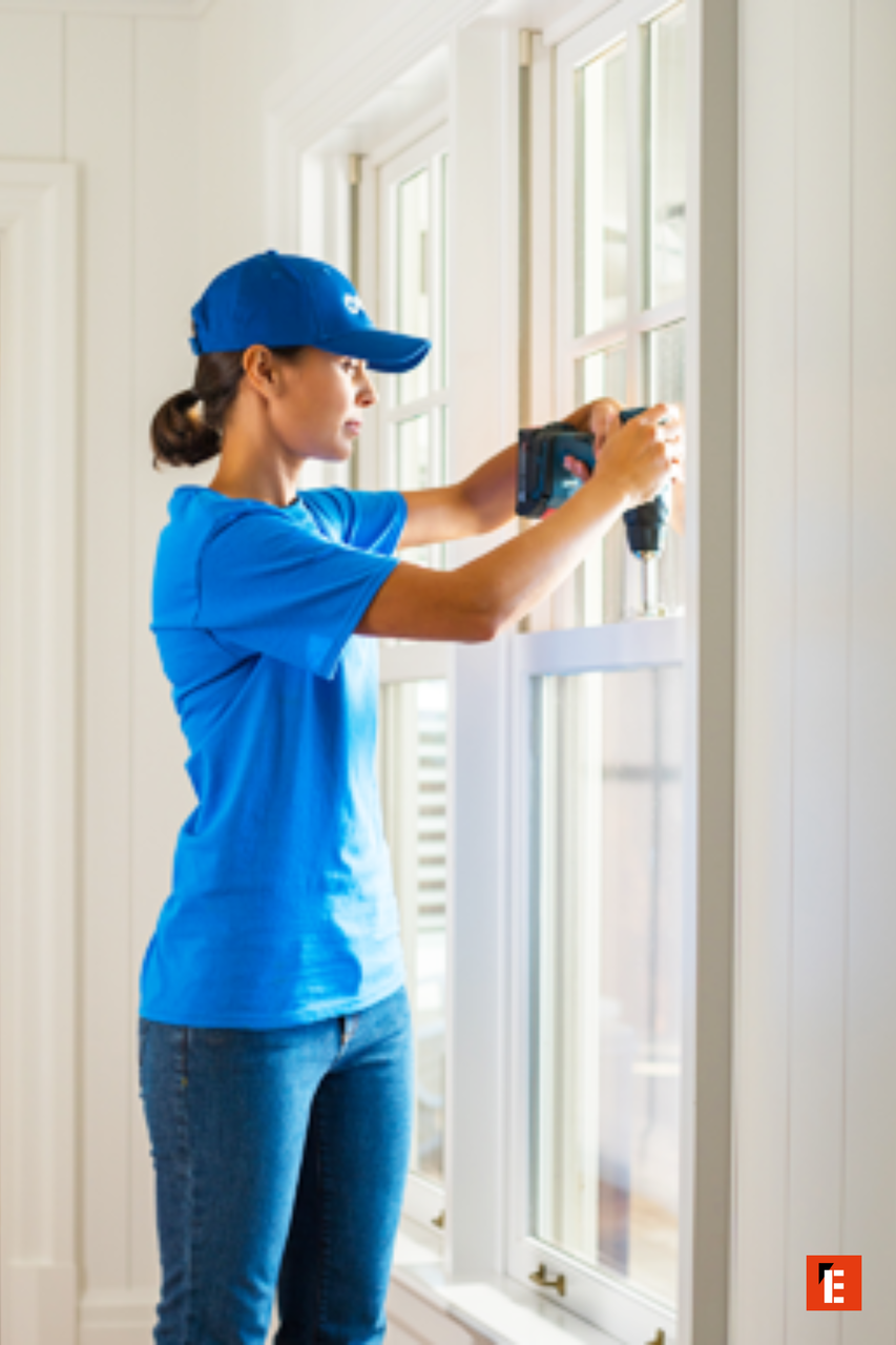 woman installing window frame with cordless drill