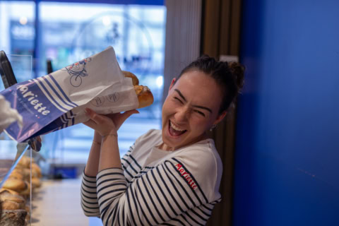 femme riante avec baguettes fraîches en boulangerie