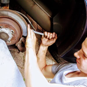 mechaniker repariert verrostete bremsscheibe am auto