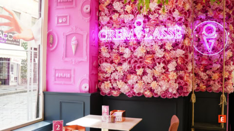 caffè rosa con insegna neon e muro di fiori
