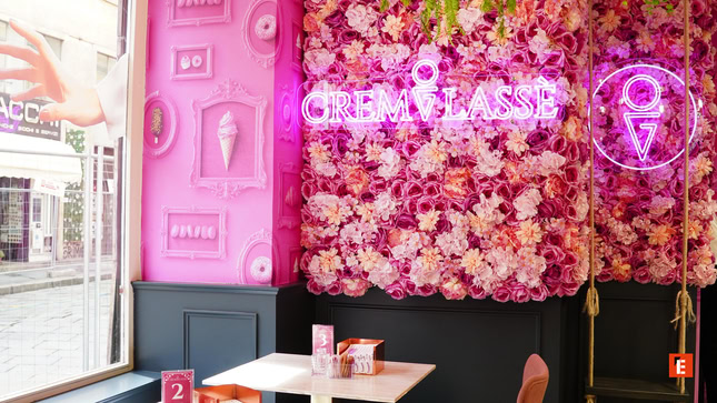caffè rosa con insegna neon e muro di fiori