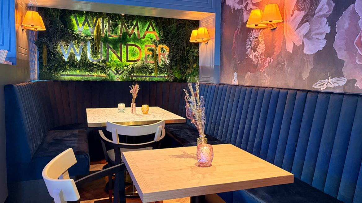 moderne café ecke mit samtbanquette und begrünter wand