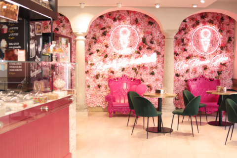 caffè rosa con parete di fiori e dolci