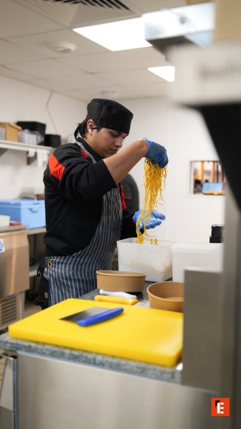 chef prepara fideos para llevar en cocina profesional