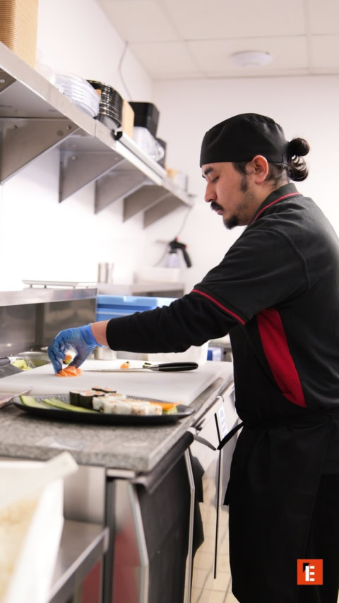 chef prepara sushi de salmón con guante azul
