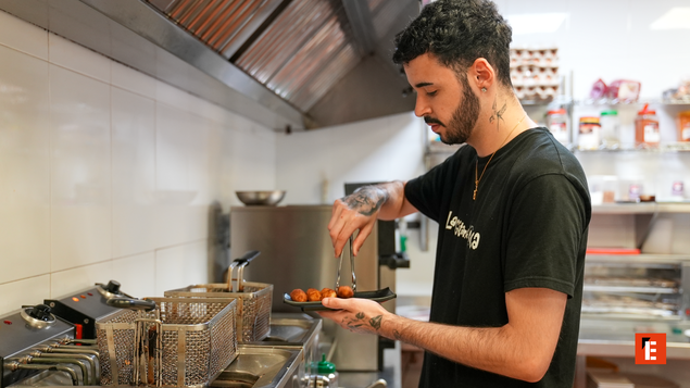 cocinero emplatando aperitivos fritos en cocina industrial