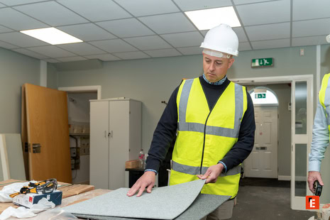 worker inspecting carpet tile during office refurbishment