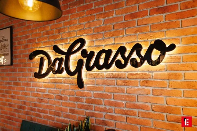 podświetlone logo dagrasso na ceglanej Ścianie