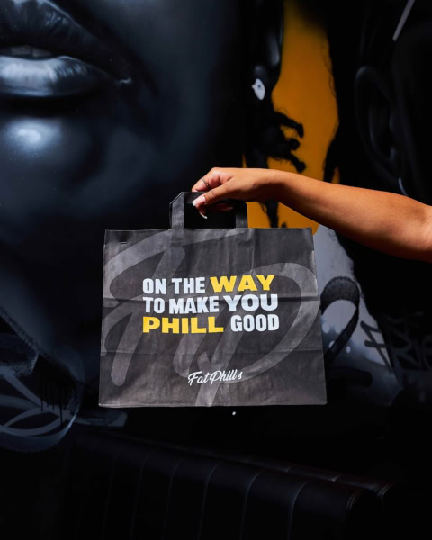 hand holding fatphills black bag against urban mural