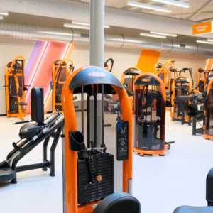 modernes fitnessstudio: kraftraum mit orangefarbigen geräten