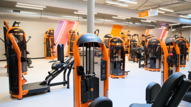 modernes fitnessstudio: kraftraum mit orangefarbigen geräten