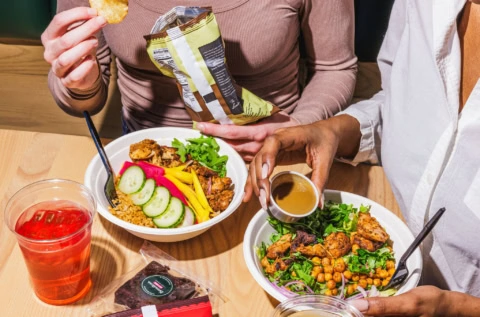 friends sharing colorful chicken and mango lunch bowls