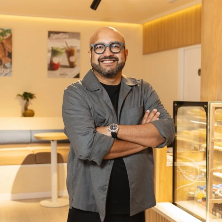 hombre sonriente en cafetería moderna junto a pastelería