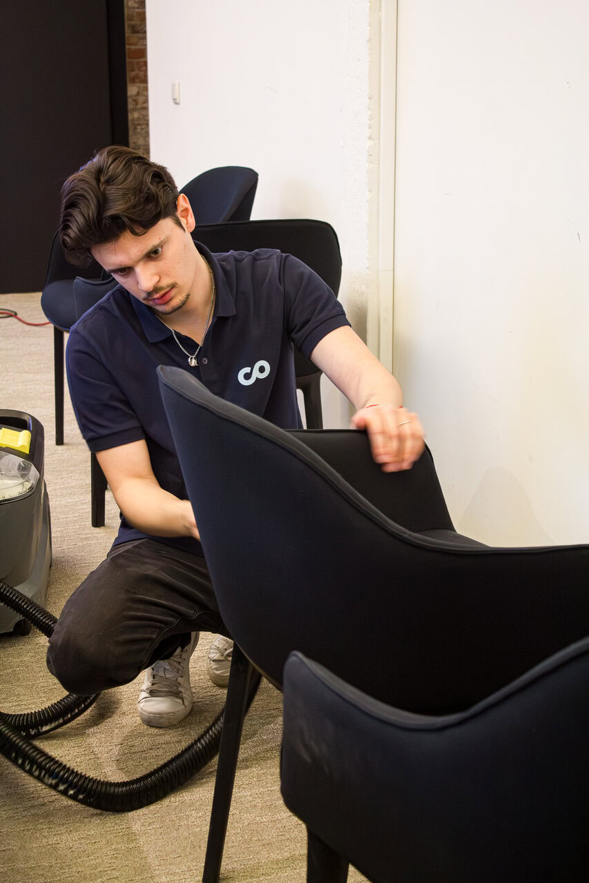 jeune homme nettoie chaises tapissées au bureau