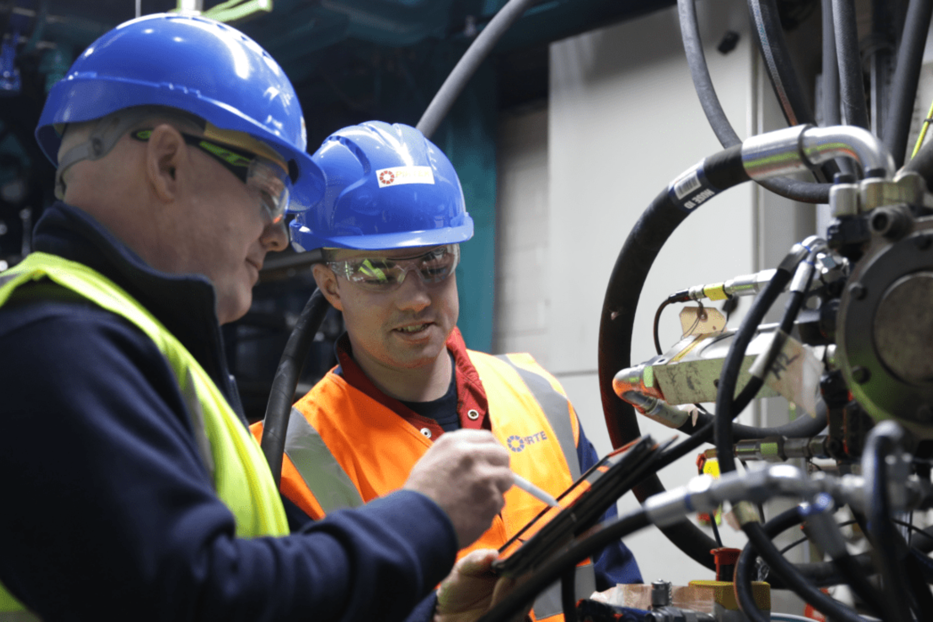 industrial workers inspecting hydraulic hoses