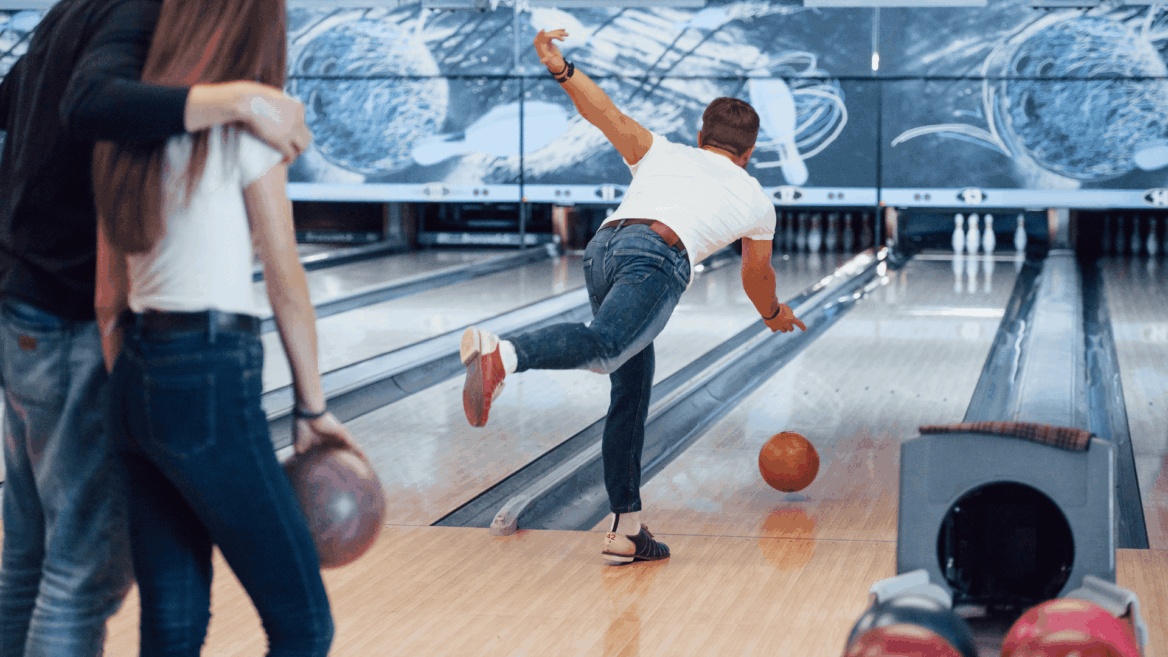 jugador de bolos lanzando bola naranja en bolera