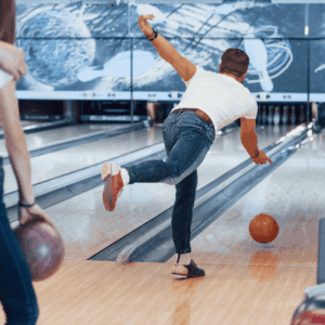 jugador de bolos lanzando bola naranja en bolera