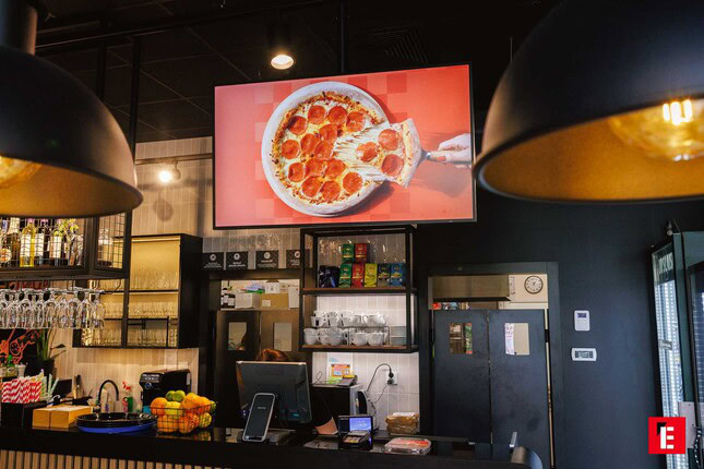 nowoczesna kawiarnia z ladą i reklamą pizzy