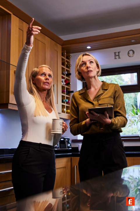 two women inspecting modern kitchen with tablet